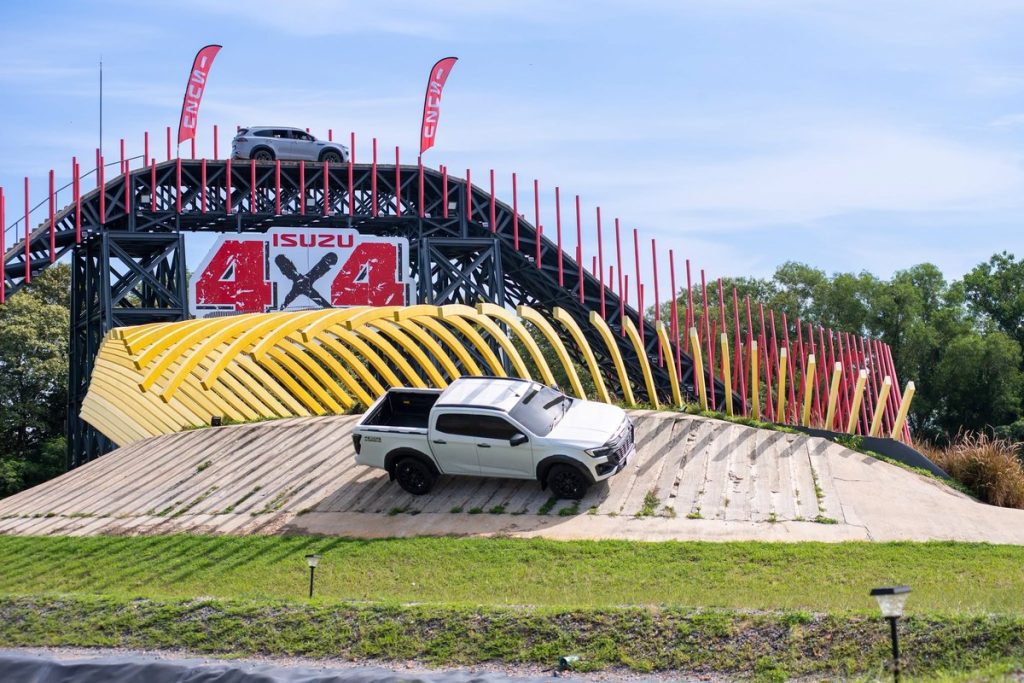 Isuzu D-Max màu trắng chạy trên đoạn dốc đá cạnh cổng vòm ISUZU 4x4 Experience