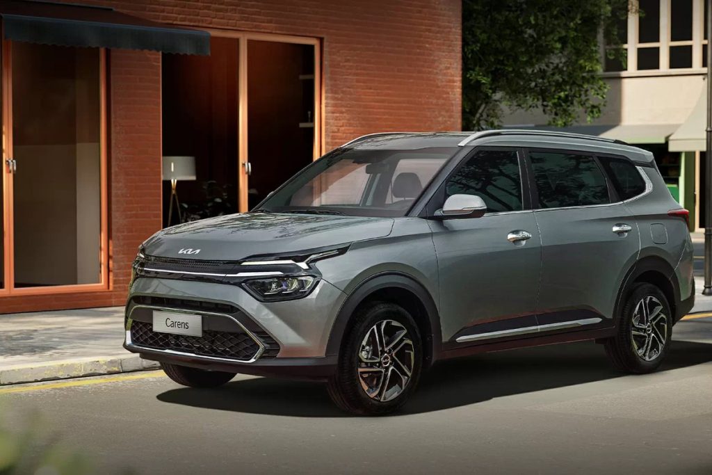 Kia Carens màu xám trước khu nhà gạch