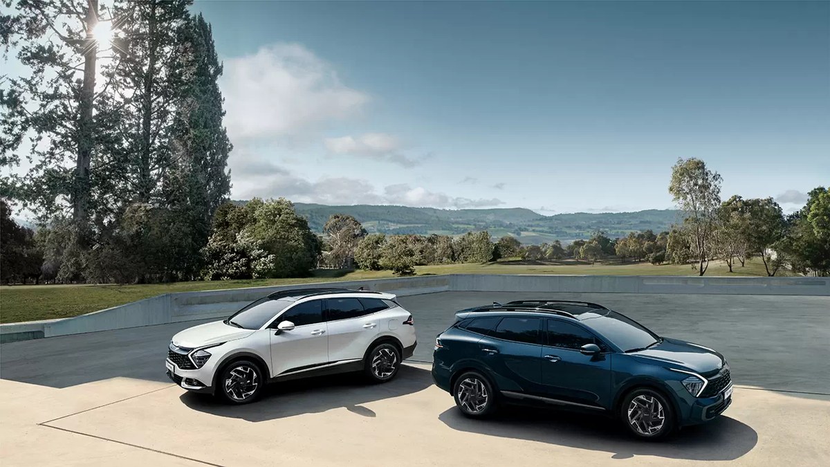 Hai chiếc Kia Sportage màu trắng và xanh đỗ trên khoảng sân rộng