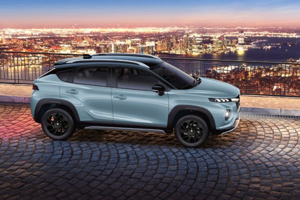 Suzuki Fronx nhìn ngang đỗ trên đường lát đá, nền thành phố về đêm
