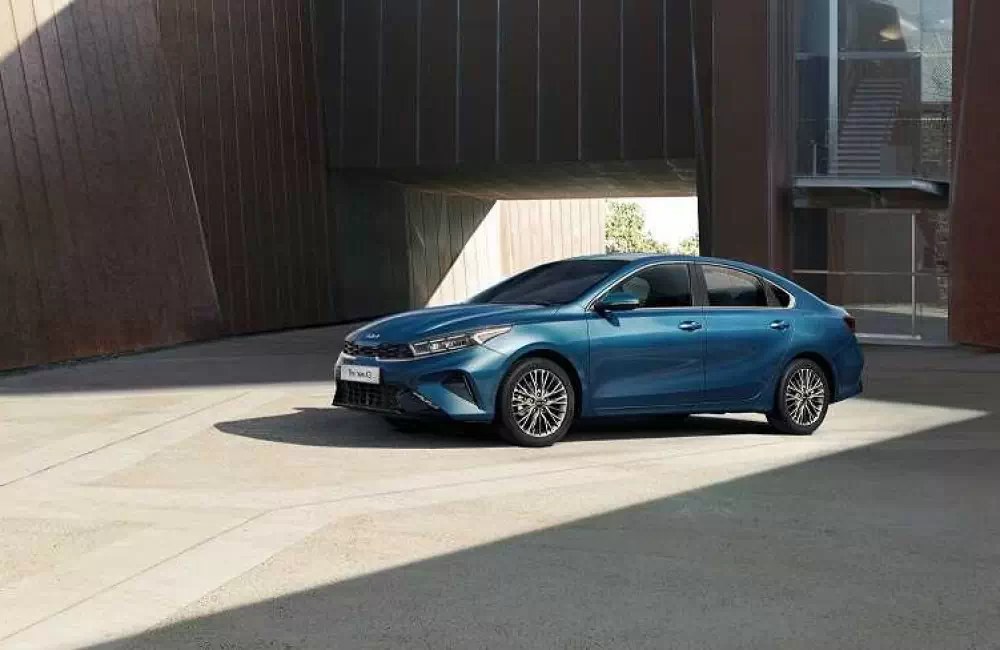 Kia K3 màu xanh đỗ trước công trình hiện đại